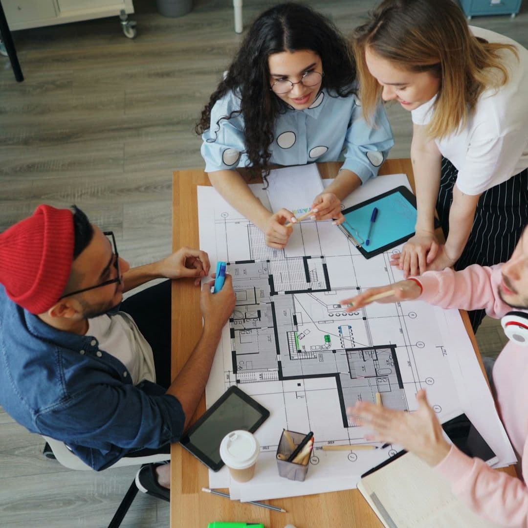 Vier Personen beraten sich zu einem Architekturplan